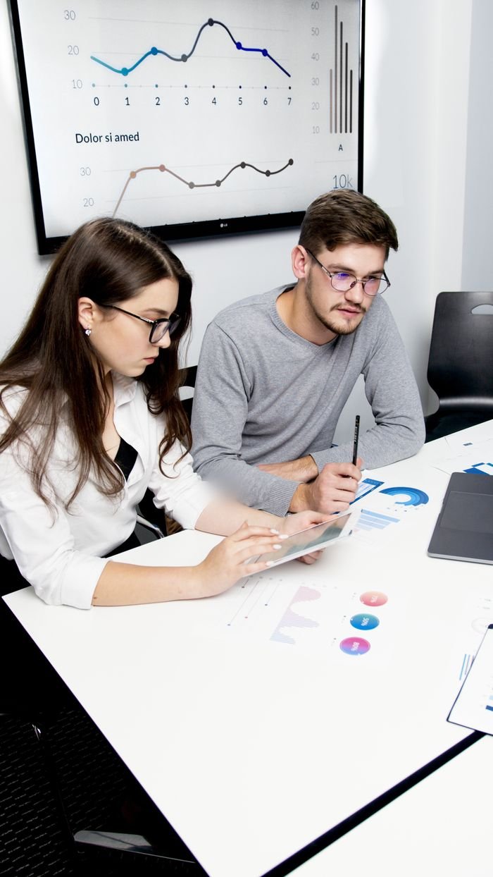 services-03 Two business professionals collaborating on financial analysis with charts and graphs.